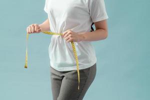 control de peso del cuidado del cuerpo saludable de las mujeres que mide la grasa de la cintura usando cinta métrica o cinta métrica. foto