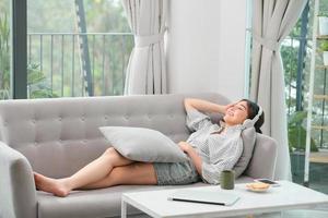 Happy young relaxed woman with headphones sitting on couch and listening to meditation music at leisure photo