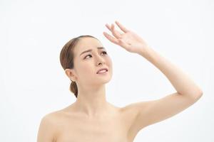 Portrait of young Asian woman looking to the side and showing hand on white background. photo