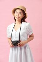 Vertical image of a young woman photographing somebody against a pink background photo