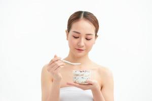 Pretty happy young pretty female eating dessert in a jar while looking away. Horizontal Shot photo