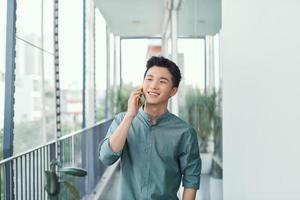 Cheerful young male talking on the phone on a balcony photo