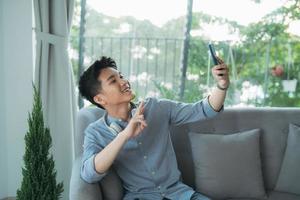 joven guapo tomando selfie con auriculares inalámbricos escuchando música foto