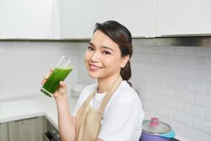 Detox Concept. Close up portrait of asian girl holding glass with homemade green juice, looking aside at free space photo