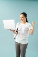 Smiling teenager with laptop on blue background photo