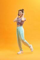 Full size view of charming young woman listening melodies via headphones over yellow background photo