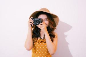 mujer joven feliz sosteniendo una cámara de fotos retro, aislada en un fondo pastel