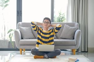Asian student with a lot of books and laptop preparing for exam at home photo