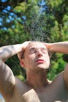 young man relaxing under shower photo