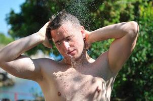 young man relaxing under shower photo