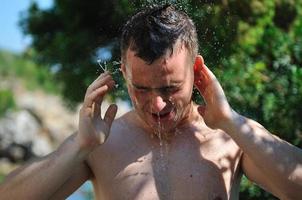 young man relaxing under shower photo