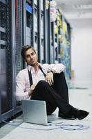 businessman with laptop in network server room photo