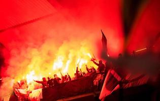 Croatia, 2022 - football hooligans with mask holding torches in fire photo