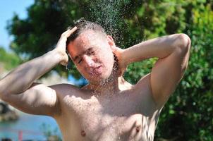 young man relaxing under shower photo