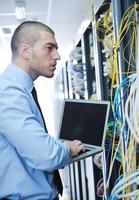 businessman with laptop in network server room photo