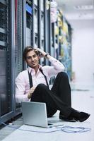 businessman with laptop in network server room photo