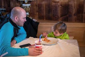 padre su pequeño hijo comiendo una pizza foto