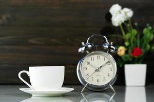 Coffee cup and alarm clock on table photo