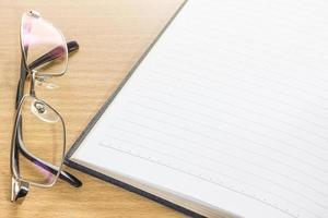 Eyeglasses and open note book with blank page photo