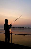 Silhouette of a man fishing photo