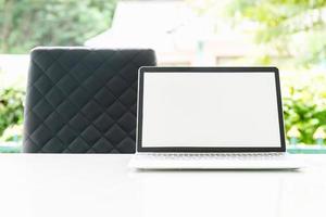 Laptop computer and cup of coffee on the table in morning photo