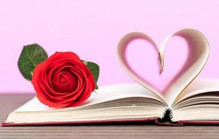 página del libro con forma de corazón curvo y rosa roja foto