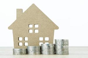 House model and stack of coins on table photo