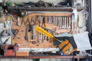 Hand in glove holding screwdriver with tools photo