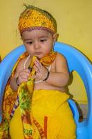lindo niño indio disfrazado de pequeño señor krishna con motivo del festival radha krishna janmastami en delhi india foto