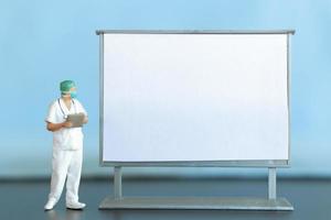 Miniature Doctor standing With Blank White Board photo