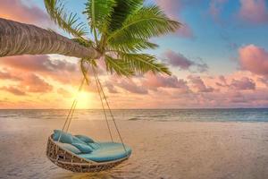 Tropical sunset beach background, summer island landscape with palm swing and sand sea sky beach. Beautiful couple beach vacation or summer holiday concept. Honeymoon, romance resort. Amazing scene photo