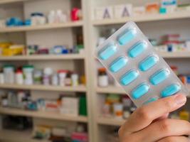 pharmacist showing medicine pills with pharmacy shelves background photo