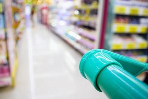 shopping cart with abstract blur supermarket discount store product shelves interior defocused background photo