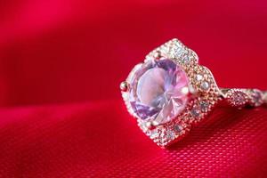 Jewelry luxury pink gold ring with sapphire gemstone on red fabric texture background photo