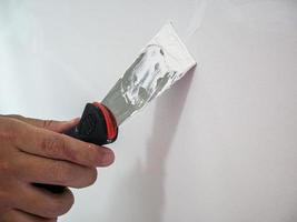 Plasterer hand repair crack white wall photo
