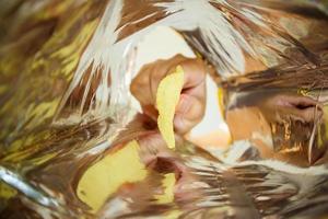 Hand hold potato chips inside snack foil bag photo