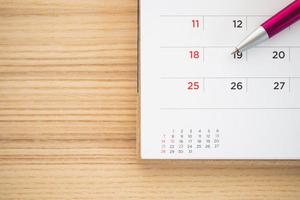 calendar page with pen on wood table background photo