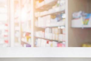 white table counter in pharmacy store interior with medicine on medical shelves blur background photo
