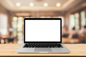 Blank screen laptop computer on wood table top with blur cafe restaurant with abstract bokeh light defocused background photo