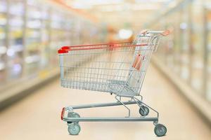 Supermarket refrigerators freezer aisle blur defocused background with empty red shopping cart photo