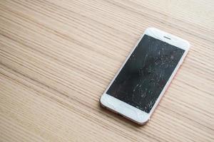 broken glass of mobile phone screen on wooden background photo