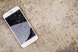 broken glass of mobile phone screen on concrete floor background photo