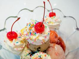 Ice cream scoops with whipped cream and cherry photo