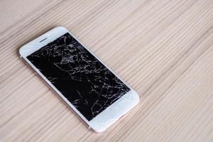 broken glass of mobile phone screen on wooden background photo