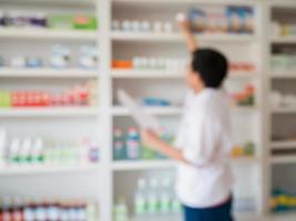 blur pharmacist taking medicine from shelf in the pharmacy photo