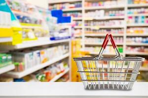 Empty shopping basket on pharmacy drugstore counter with blur shelves of medicine and vitamin supplements background photo