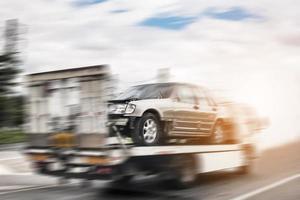 Broken car on tow truck after traffic accident, on the road service photo