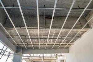Install metal frame for plaster board ceiling at house under construction photo