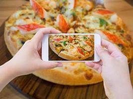 mujer tomando fotos de pizza y con teléfono inteligente móvil