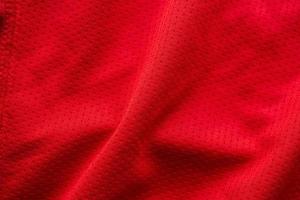 camiseta de fútbol de ropa deportiva de tela roja con fondo de textura de malla de aire foto